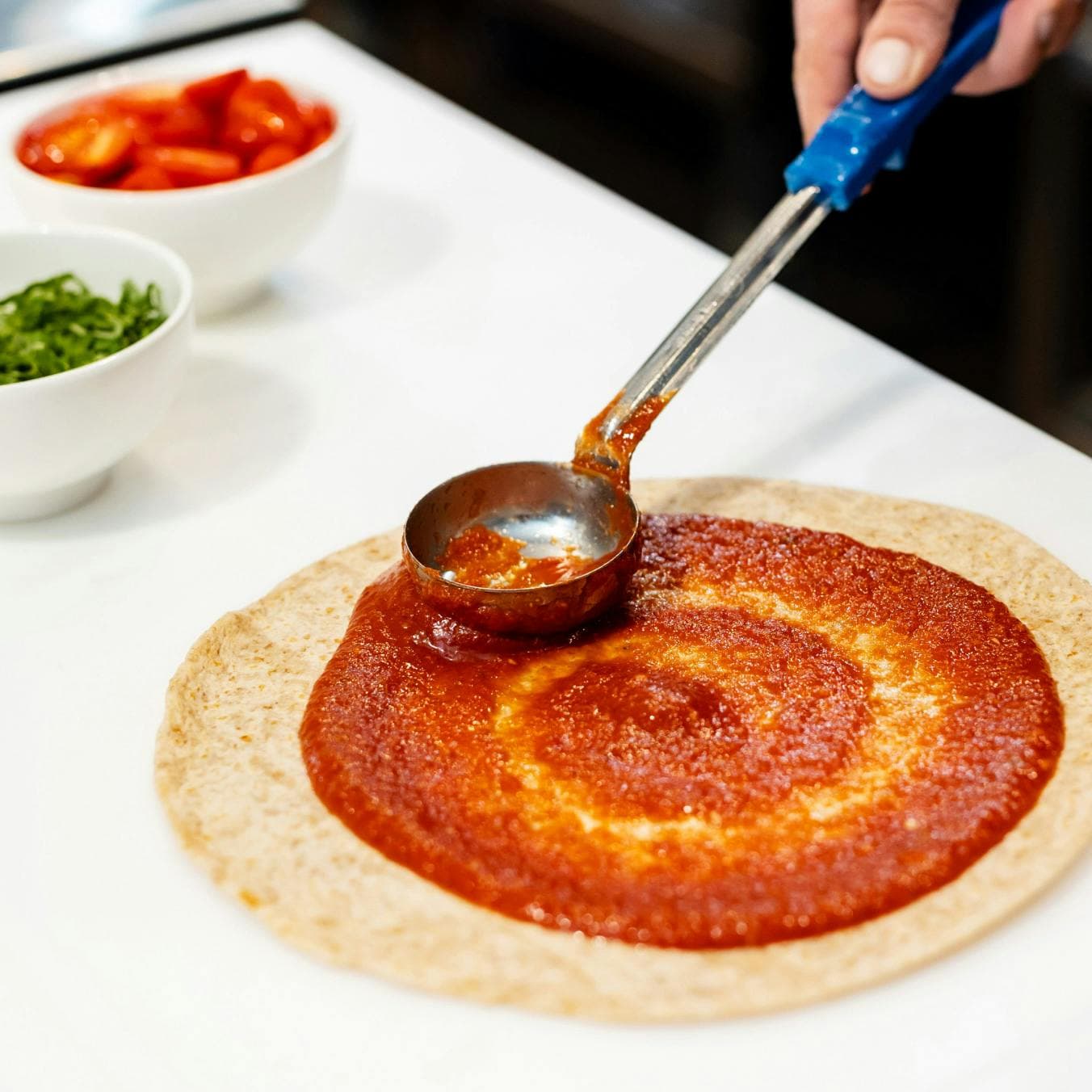 sauce being spread on pizza